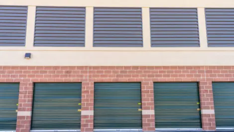 Close up of outdoor storage units with green doors, brick building at Towne Storage-Clinton