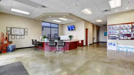 Wide view of the office area with desk, seating, storage supplies, dollies, and security tv at Towne Storage Buffalo