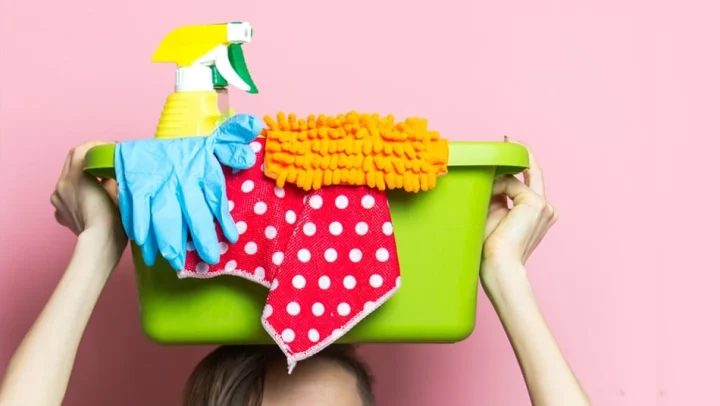 A person balances a box of cleaning supplies on their head